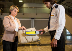 Airport security officer using a metal detector to check a bag in airport